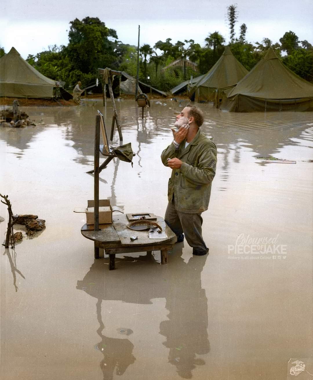 Le sergent américain S. Barnacle se rasant, les pieds dans l'eau, suite à la mousson, le 28 mai 1945 à Okinawa, Japon