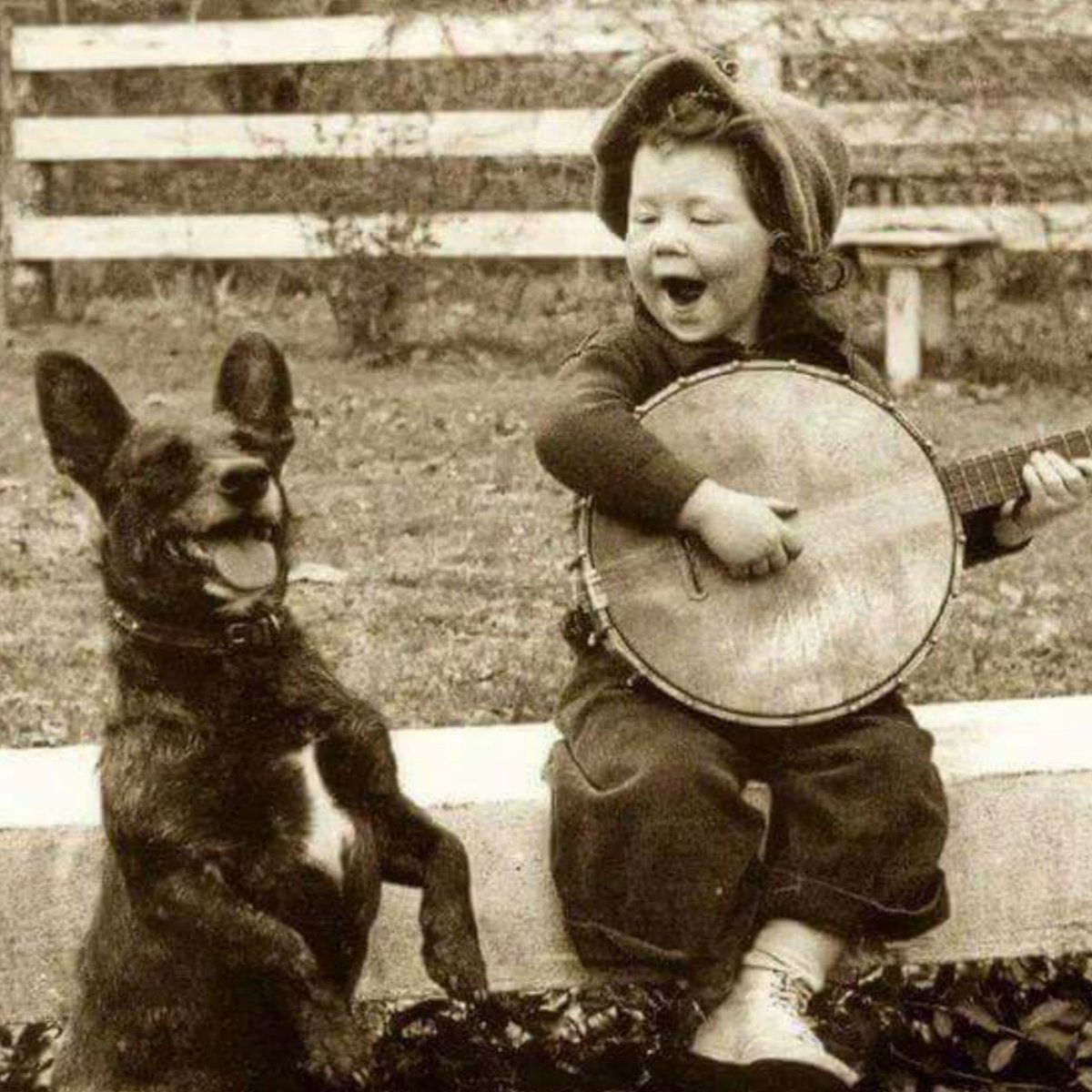 Un petit garçon jouant du banjo au côté de son chien, 1920