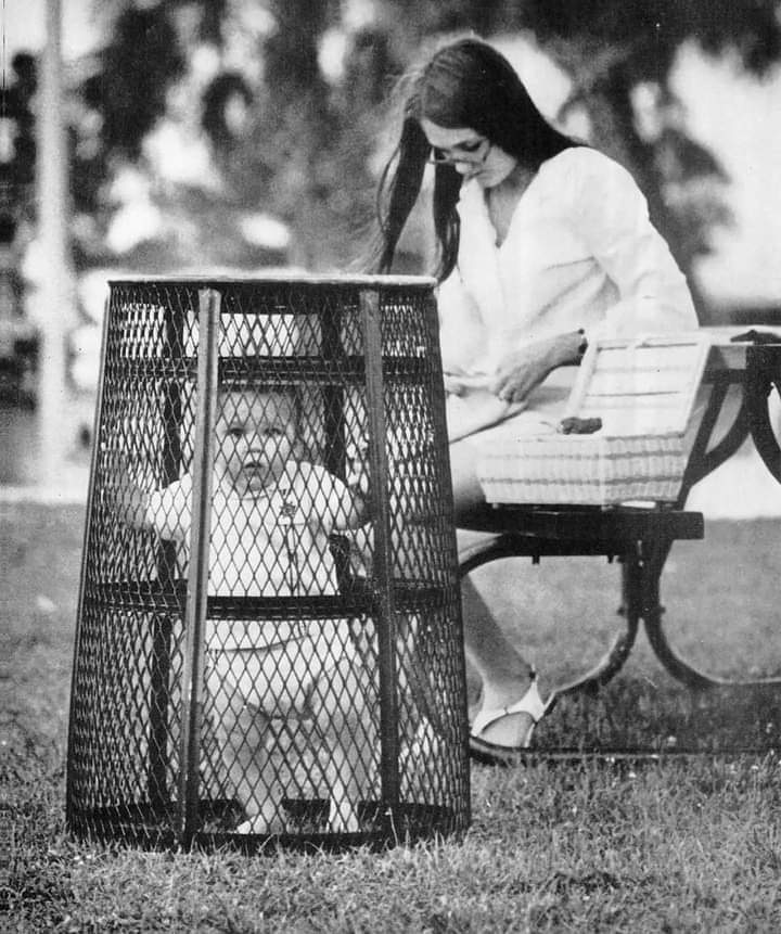 Une maman utilise une poubelle pour contenir son bébé pendant qu'elle crochète dans le parc, 1969